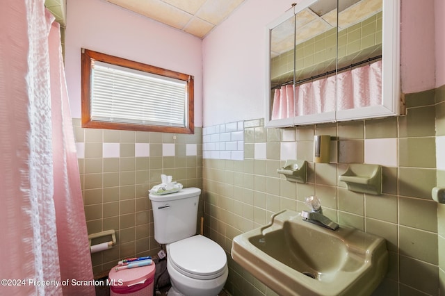 bathroom with sink, tile walls, and toilet