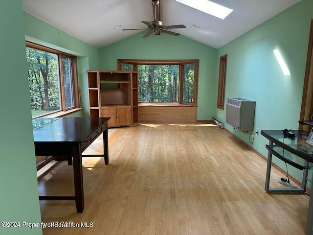 unfurnished office featuring light wood-type flooring, heating unit, lofted ceiling with skylight, ceiling fan, and a baseboard heating unit