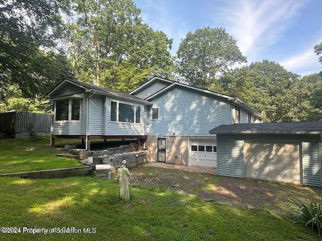 back of house with a garage and a lawn