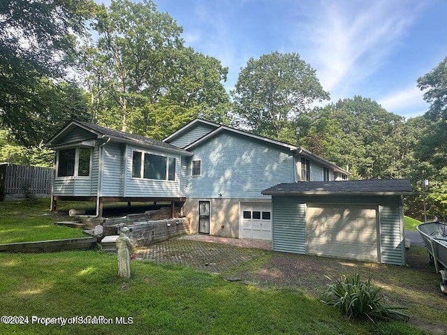 back of property with a lawn and a garage