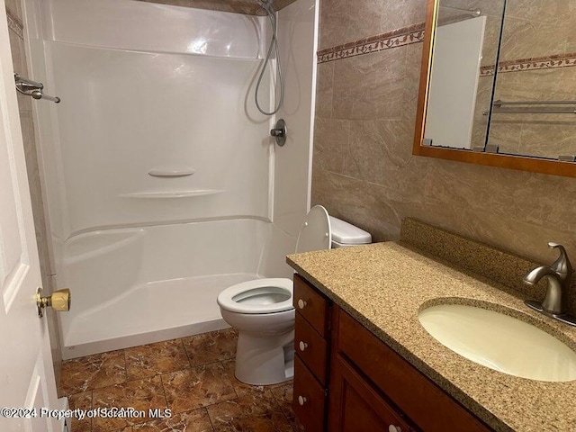 bathroom featuring a shower, vanity, tile walls, and toilet