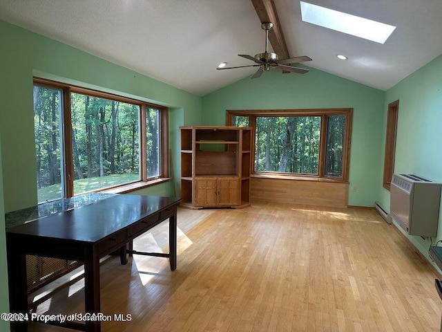 interior space featuring ceiling fan, light wood-type flooring, lofted ceiling with skylight, and a baseboard heating unit