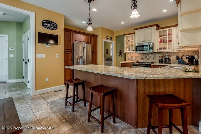 268 Winship Rd, Covington Twp, PA 18444 - kitchen with appliances with stainless steel finishes, a peninsula, light stone counters, backsplash, and glass insert cabinets