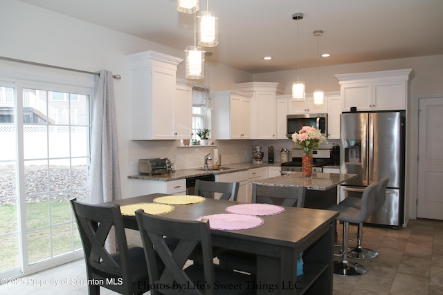 kitchen featuring appliances with stainless steel finishes, decorative backsplash, a sink, and white cabinetry