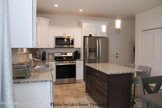 kitchen with a sink, white cabinets, appliances with stainless steel finishes, and a kitchen breakfast bar