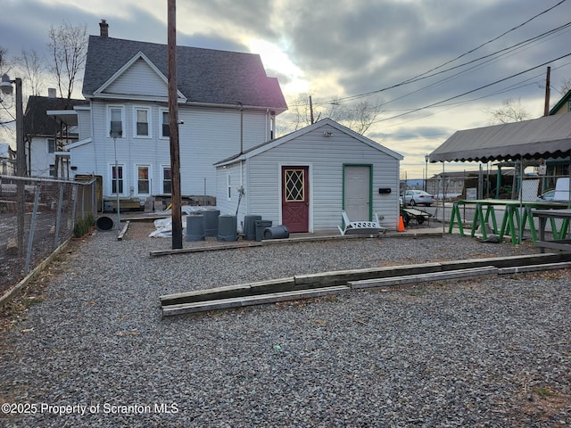 back of property with an outdoor structure and fence