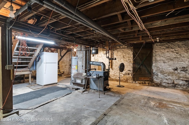 basement with gas water heater and white refrigerator