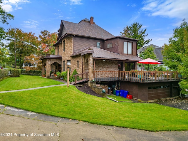 rear view of house with a garage, a yard, and a wooden deck