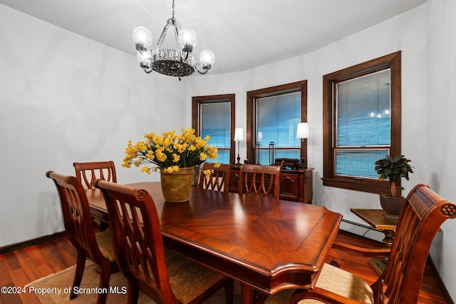 dining area featuring hardwood / wood-style floors, a notable chandelier, and a baseboard heating unit