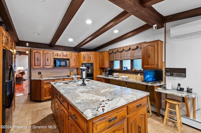 kitchen with light stone countertops, baseboard heating, sink, black appliances, and a center island with sink