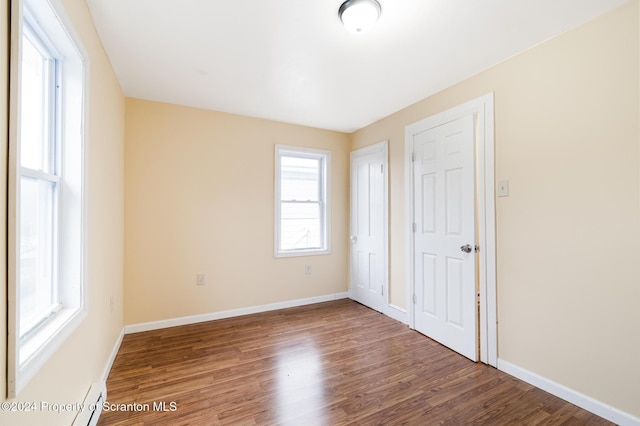 unfurnished bedroom featuring multiple windows and wood-type flooring