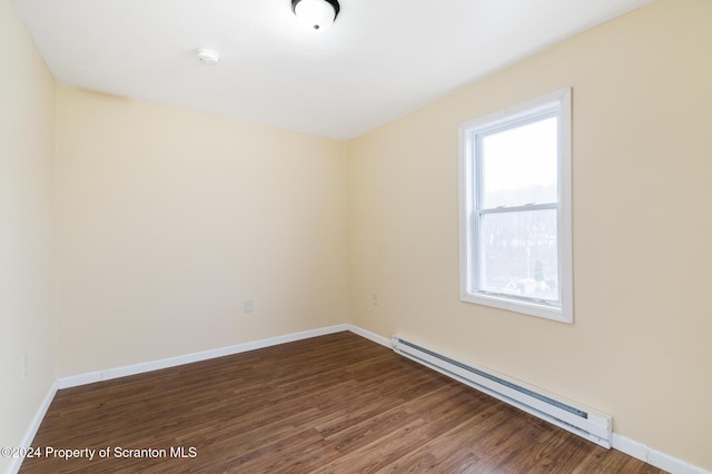 empty room featuring dark hardwood / wood-style flooring and a baseboard heating unit