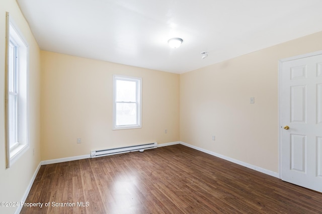 empty room with dark hardwood / wood-style floors and a baseboard heating unit