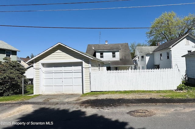 view of front of home with fence, an outbuilding, and an attached garage