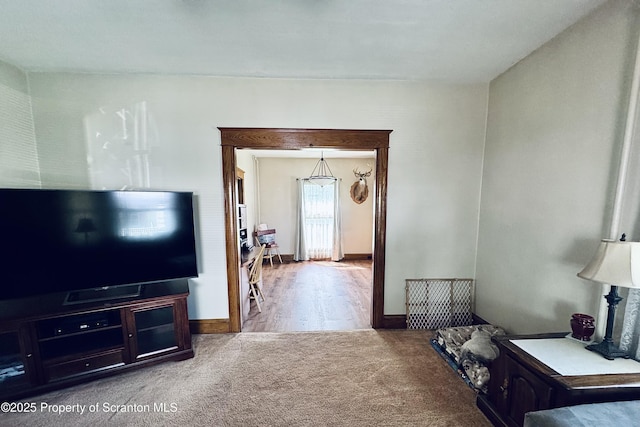 carpeted living area featuring baseboards
