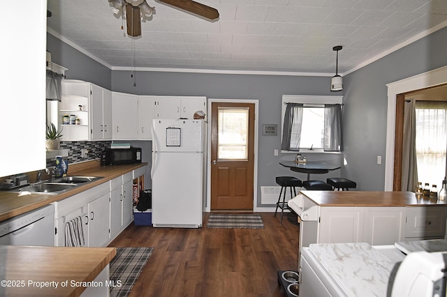 kitchen featuring black microwave, a sink, freestanding refrigerator, white cabinetry, and dishwashing machine