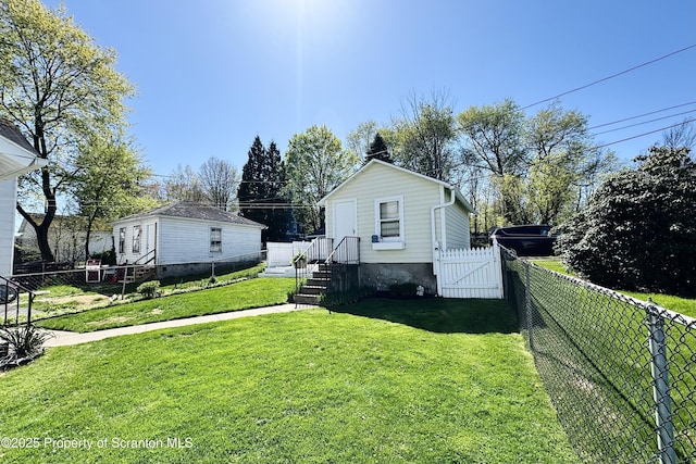 exterior space with a fenced backyard, a gate, and a lawn