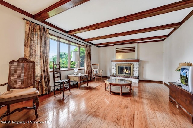 sitting room featuring a fireplace, light hardwood / wood-style flooring, and beamed ceiling