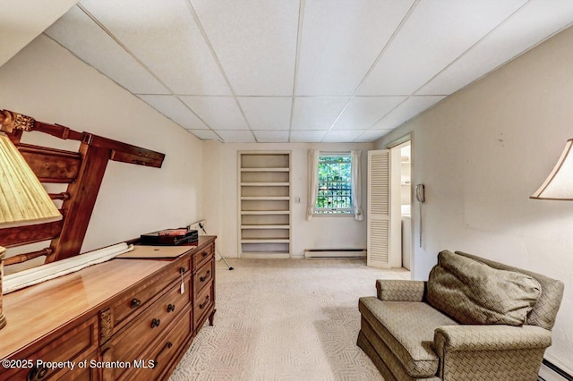 living area with light colored carpet, a paneled ceiling, built in features, and a baseboard radiator