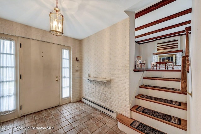 entryway with baseboard heating, brick wall, and an inviting chandelier