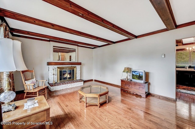 living room with beam ceiling, a brick fireplace, an inviting chandelier, and hardwood / wood-style floors