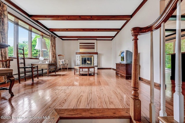 living area with beamed ceiling, a fireplace, wood-type flooring, and a baseboard radiator