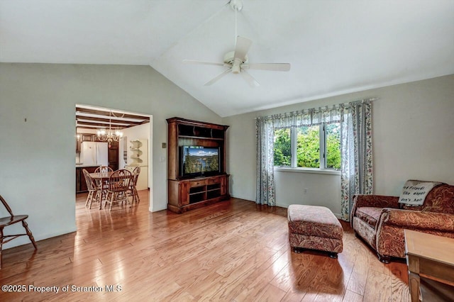 living room featuring vaulted ceiling, ceiling fan with notable chandelier, and light hardwood / wood-style flooring