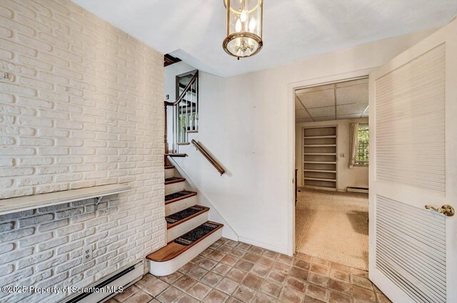 stairway with a baseboard radiator, a chandelier, and carpet flooring