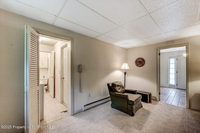 sitting room featuring a paneled ceiling, baseboard heating, and light colored carpet