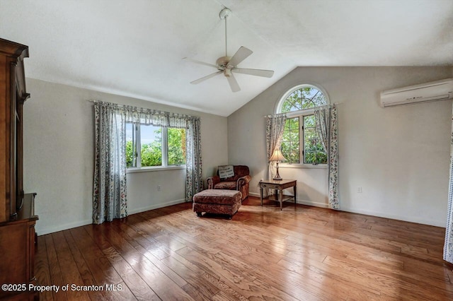 sitting room featuring an AC wall unit, a wealth of natural light, hardwood / wood-style flooring, and lofted ceiling