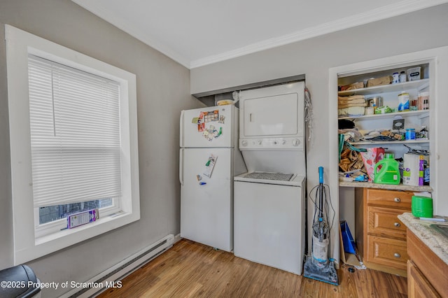 washroom with light wood-type flooring, stacked washer / dryer, crown molding, and baseboard heating