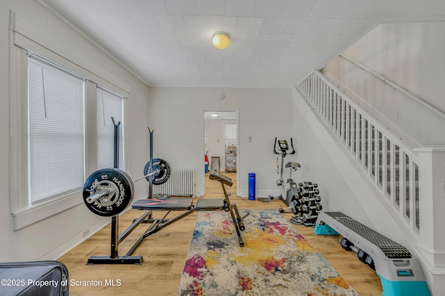 workout area featuring hardwood / wood-style flooring, ornamental molding, a wealth of natural light, and radiator heating unit