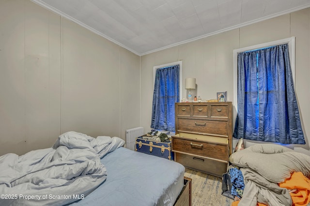 bedroom with ornamental molding, wood-type flooring, and radiator heating unit