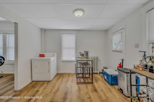 washroom featuring light hardwood / wood-style floors, washer / dryer, radiator, and a healthy amount of sunlight