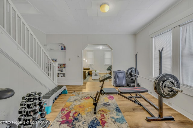 exercise area featuring ornamental molding and wood-type flooring