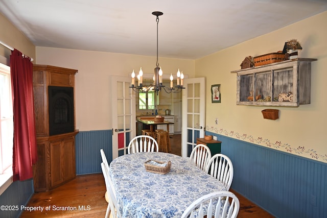 519 Sutton Rd, New Milford, PA 18834 - dining space with wainscoting, wood finished floors, healthy amount of natural light, a chandelier, and french doors