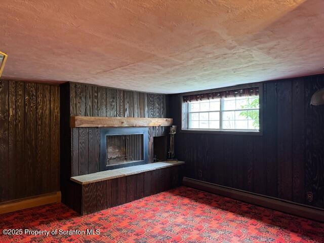 unfurnished living room with wooden walls and a fireplace with raised hearth