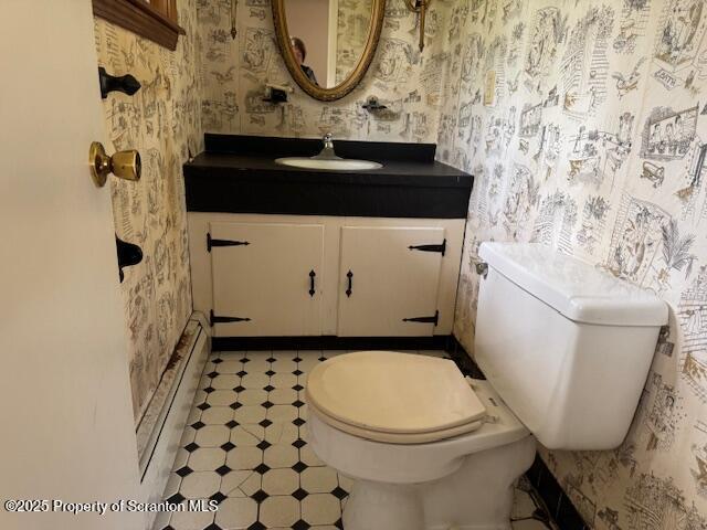 bathroom with vanity, toilet, baseboards, and wallpapered walls