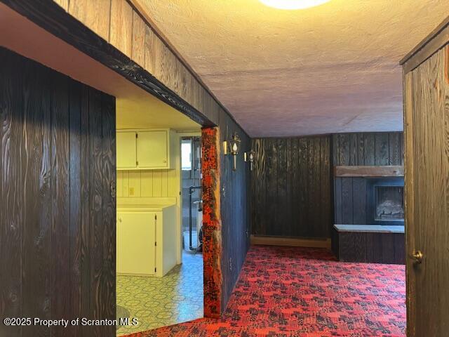 hallway with wooden walls, tile patterned floors, and a textured ceiling