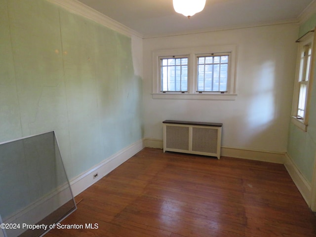 unfurnished room featuring crown molding, radiator heating unit, and dark hardwood / wood-style flooring