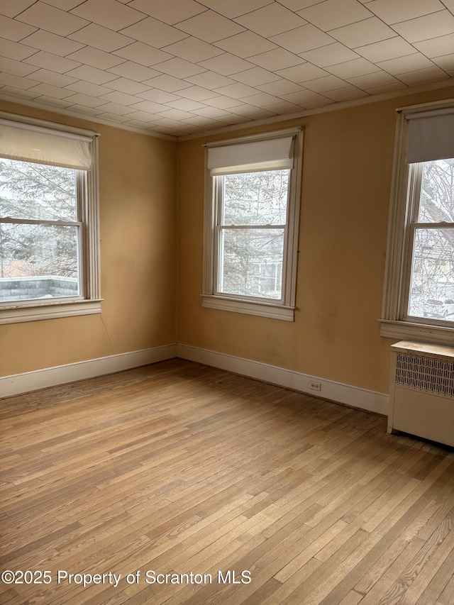 empty room featuring radiator and light hardwood / wood-style flooring