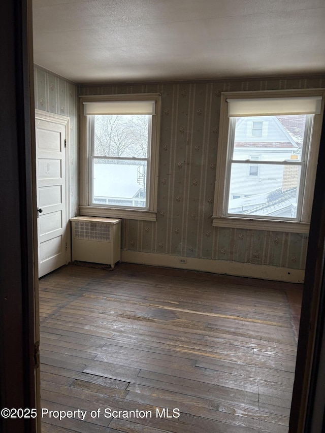 spare room featuring a wealth of natural light, radiator, and hardwood / wood-style floors