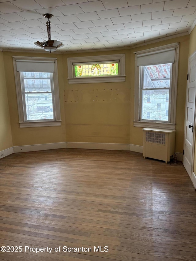 unfurnished room featuring a healthy amount of sunlight, radiator, and wood-type flooring