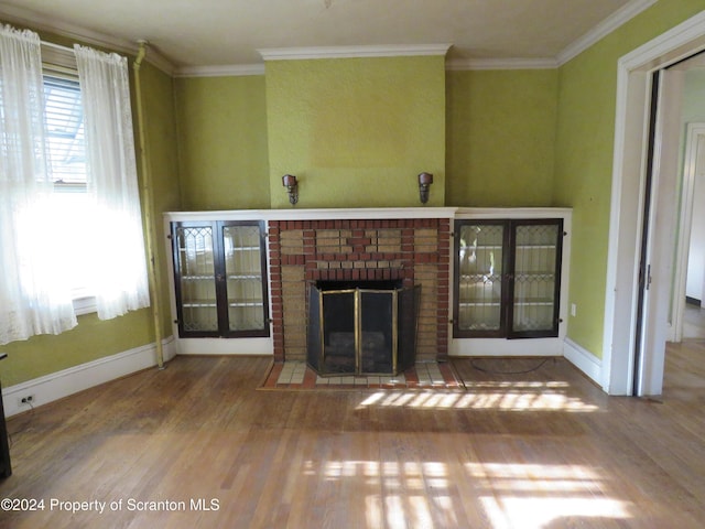 unfurnished living room with a brick fireplace, crown molding, and hardwood / wood-style floors