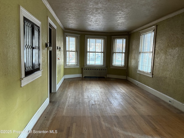 unfurnished dining area featuring crown molding, radiator heating unit, hardwood / wood-style floors, and ceiling fan