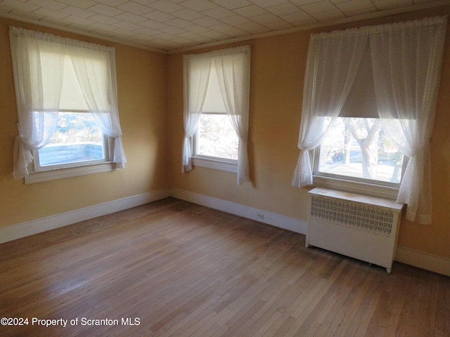 spare room featuring a healthy amount of sunlight, light hardwood / wood-style flooring, and radiator