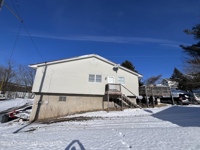 snow covered rear of property with a wooden deck