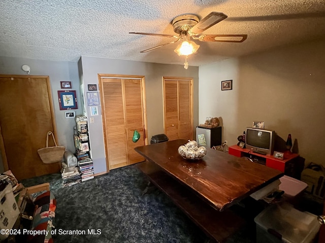 dining space with ceiling fan, carpet floors, and a textured ceiling