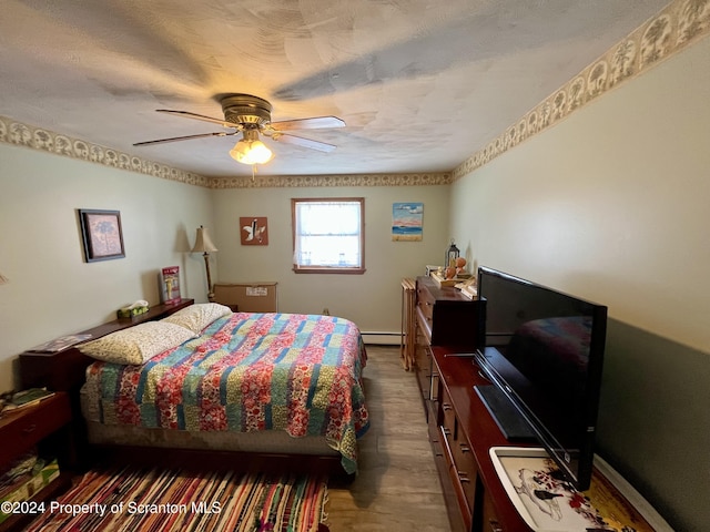 bedroom featuring a baseboard heating unit, dark hardwood / wood-style floors, a textured ceiling, and ceiling fan