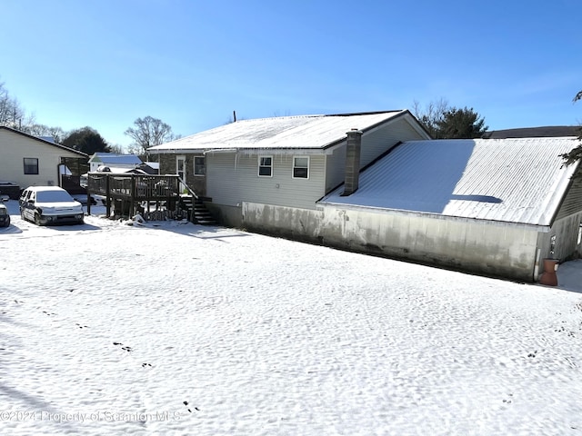 snow covered back of property featuring a deck